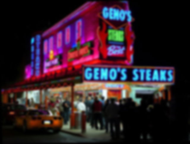 On a dark night, bright neon signs await a queue of people at “Gino's” waiting for their food