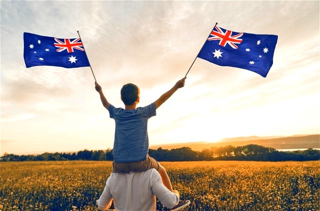 A child waving the Australian flag on his father