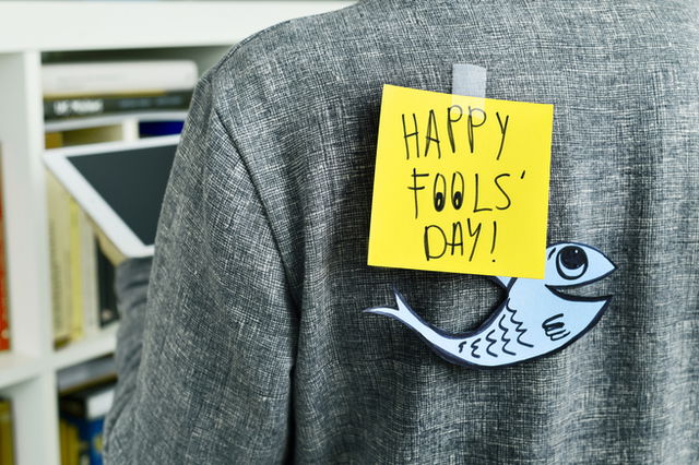 A jacket being worn, attached to their back a post it note that says “Happy Fools’ Day!