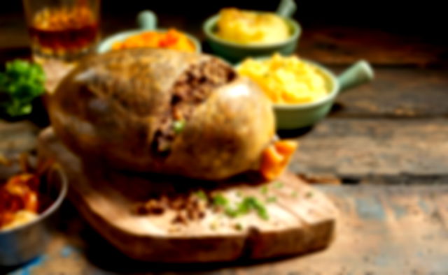 Haggis on a board, surrounded with bowls of potato and swede