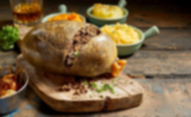 Haggis on a board, surrounded with bowls of potato and swede