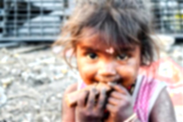 A girl in an Indian slum eats a small chocolate bar