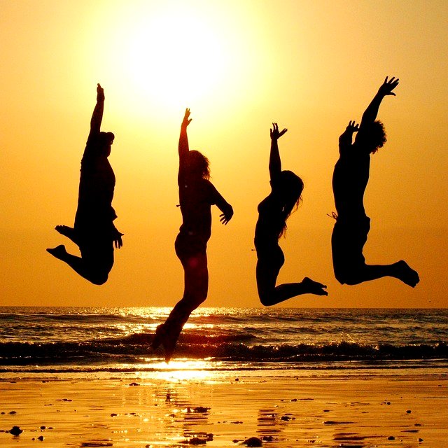 4 people jumping on the beach at sunset