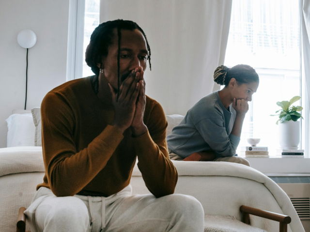 Unhappy black couple sitting on bed after having argument