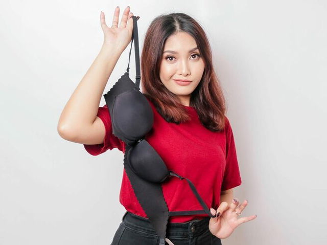 Woman holding a bra against a white background