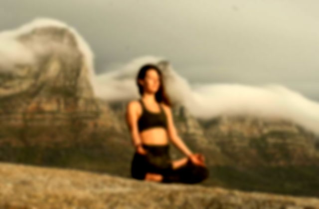 Woman in Black Sports Bra and Black Pants meditating near mountains
