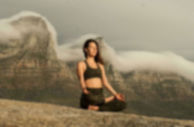 Woman in Black Sports Bra and Black Pants meditating near mountains