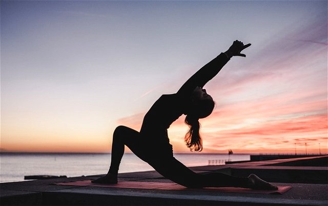 A women doing yoga near the beach at dawn