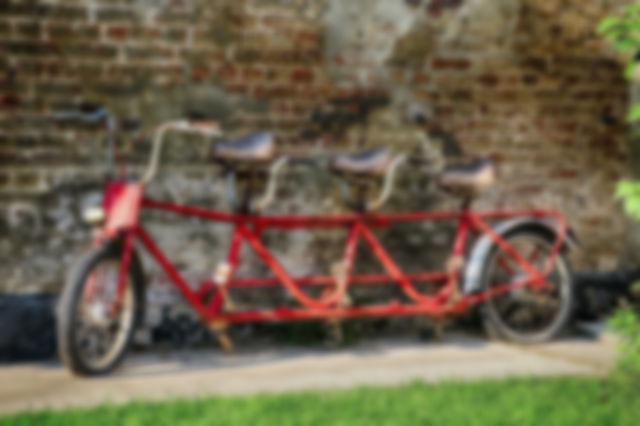 A red tandem bike propped against a wall