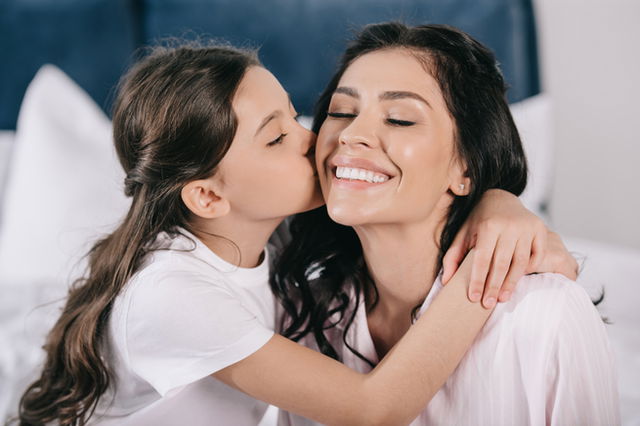 día de la madre: niña besando la mejilla de su madre