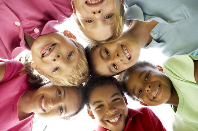 grupo de niños en círculo sonriendo a la cámara