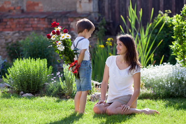 dia de la madre: niño regalando un ramo de rosas a su madre