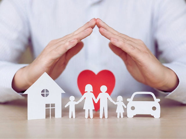 corretor de seguros com mãos sobre casa, carro e família