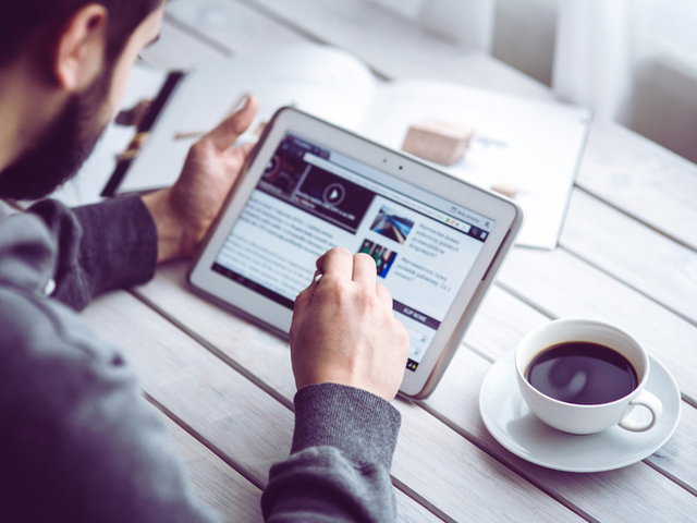 homem tomando café e usando tablet