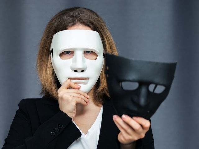 mulher usando máscara branca de teatro e segurando máscara preta na outra mão