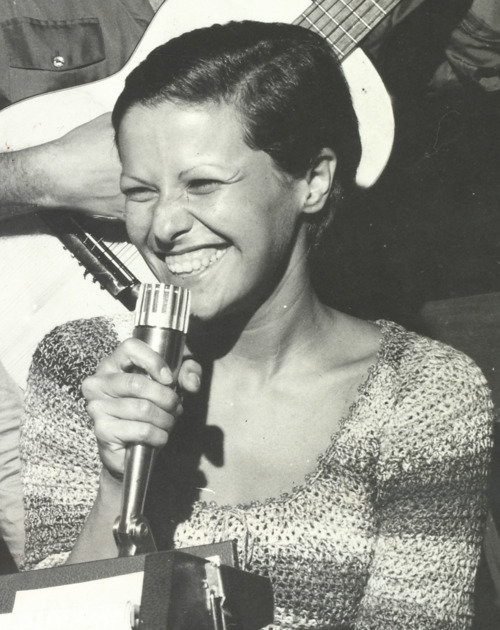 Elis Regina sorrindo com microfone na mão