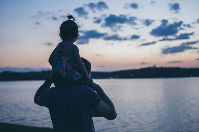 A daughter being carried on her father‘s shoulders.