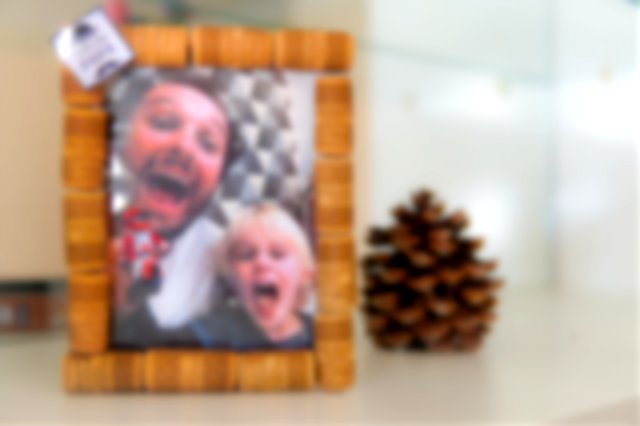 On a mantelpiece, a handmade photo frame made of cork, with a picture of a father and son.