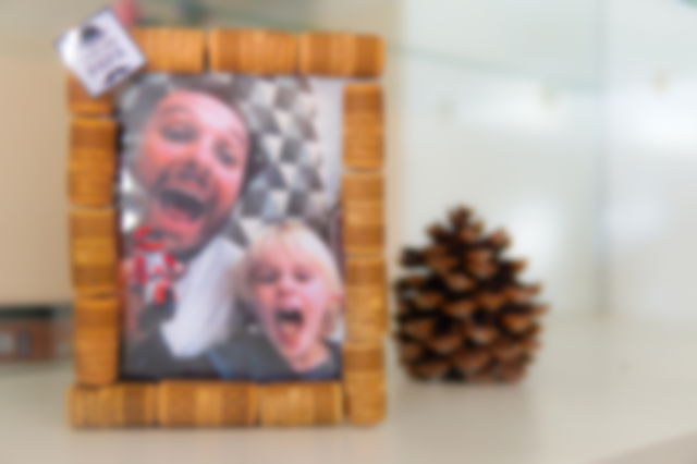 On a mantelpiece, a handmade photo frame made of cork, with a picture of a father and son.