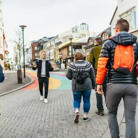 Tour guide leading a small group of people on a walking food tour through a colorful street in downtown Reykjav&iacute;k.