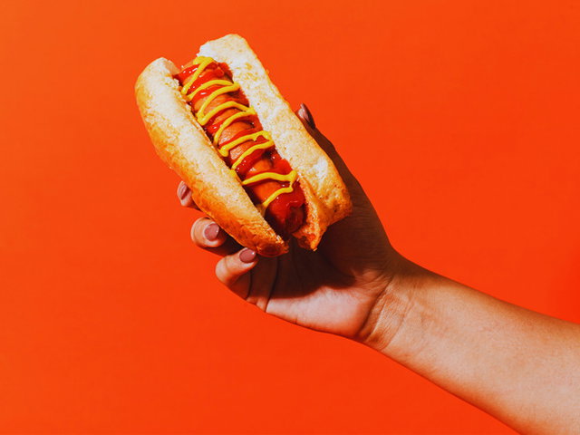 mão segurando hot dog