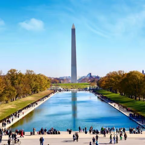 Wide view of the Milky Way arching across a dark night sky above a desert landscape with silhouetted hills.