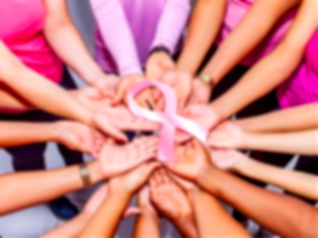 Imagen en la que aparecen manos de mujeres sosteniendo un lazo rosa