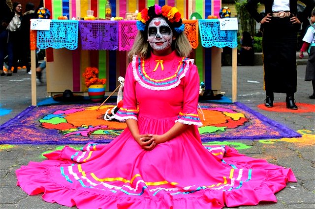 A lady sat on the ground, celebrating all souls day in costume
