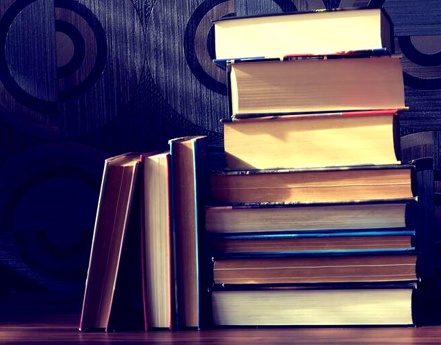 A pile of 8 different books, three more books leant again the pile.