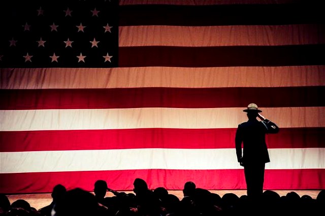 Soldier saluting on stage in front of a large American flag