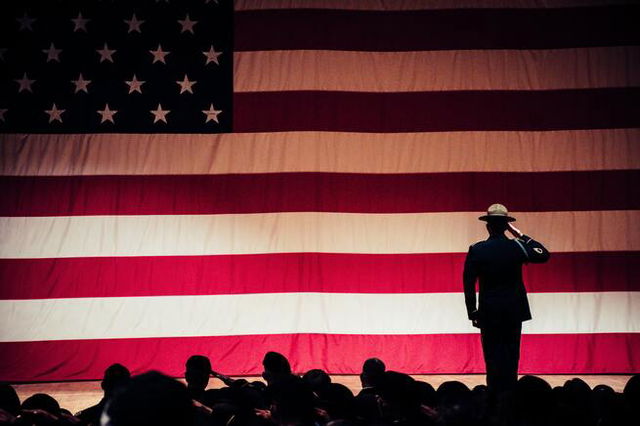 Soldier saluting on stage in front of a large American flag