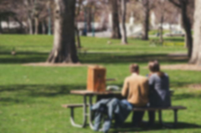 Man and Woman Sitting on Brown Wooden Picnic Table