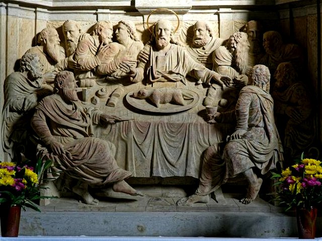 In stone, the image of the last supper is carved. Jesus has a halo,