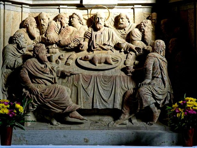 In stone, the image of the last supper is carved. Jesus has a halo,