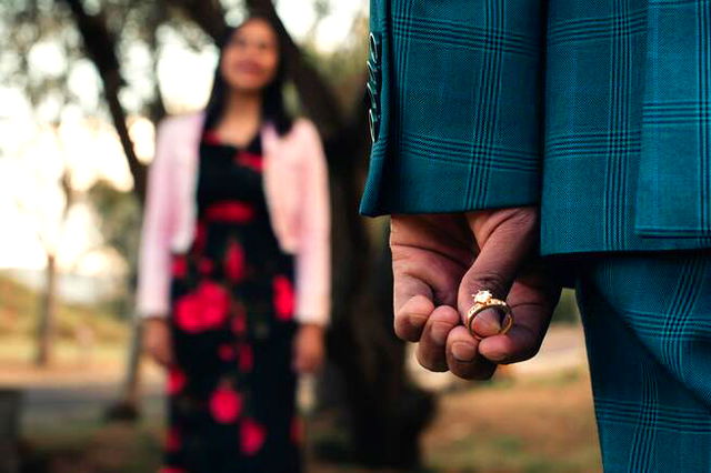 A man holding an engagement ring behind his back