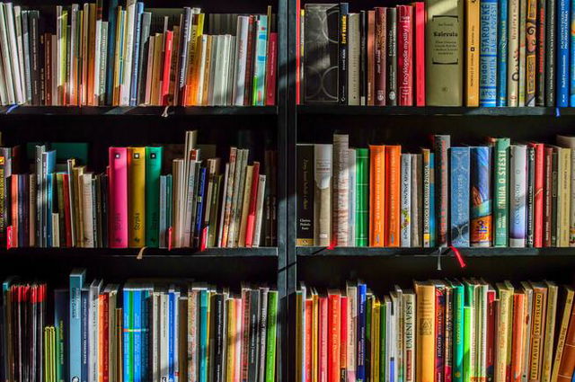 three shelves of colourful books with different heights and widths