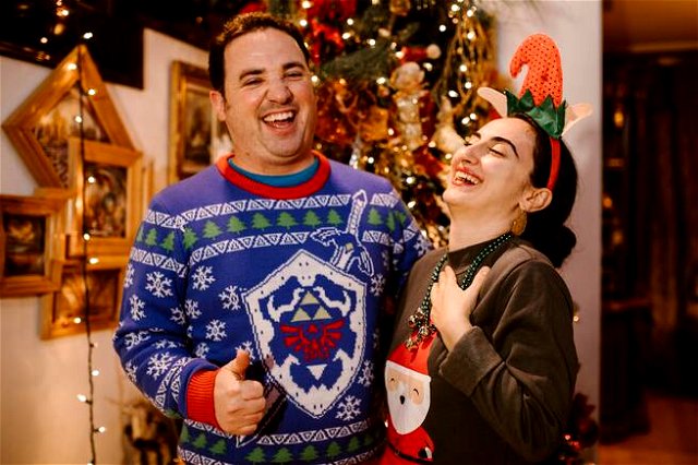 Two people laughing. One wearing ‘Link Awakening’ theme sweater, the other with Father Christmas on
