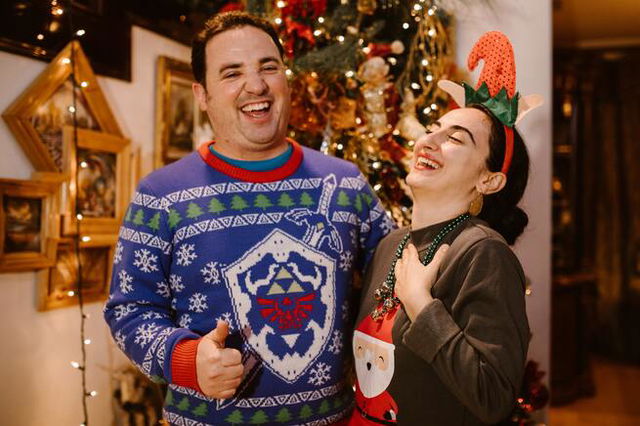 Two people laughing. One wearing ‘Link Awakening’ theme sweater, the other with Father Christmas on