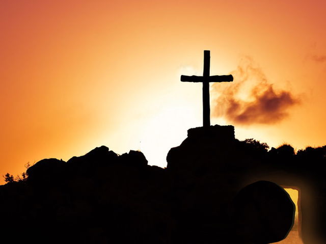 túmulo de Jesus com pedra removida com cruz em céu cor de laranja