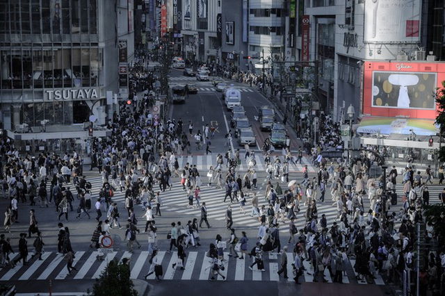 Shibuya crossing, a busy interchange with people crossing in every direction, a dull grey image