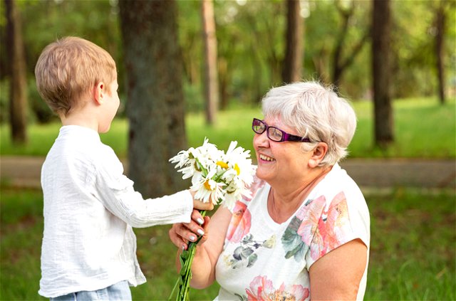 A kind Boy offering flowers to an old lady