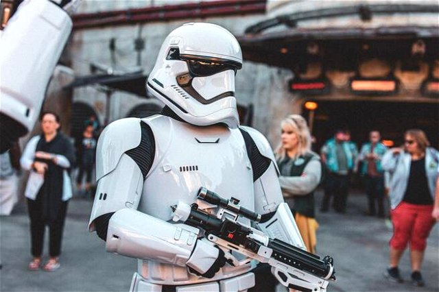 A stormtrooper in white looks at the camera, holding a science fiction gun in a street parade