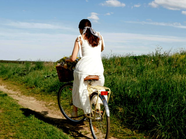 A woman cycling though the fields