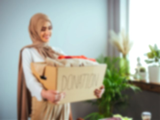 A Muslim woman giving sadaqah or charity